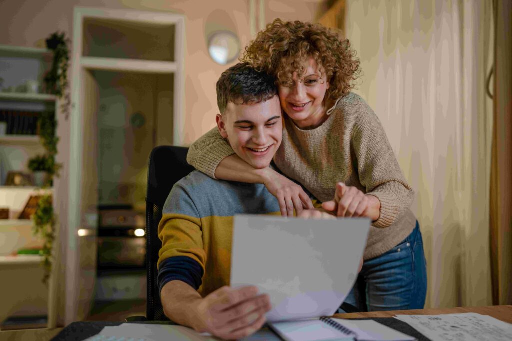 Vrouw kijkt op papier van jongen met arm om zijn schouders | MBO Kompas2 026