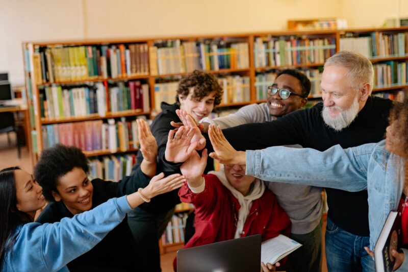 Oudere man in bibliotheek steekt hand uit naar leerlingen